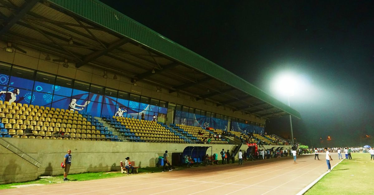 A vibrant night sports event at an outdoor stadium with athletes and spectators enjoying the game.
