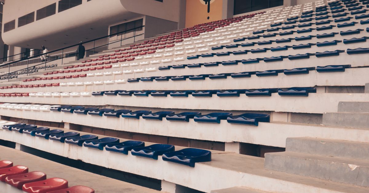 Empty grandstand with red, white, and blue seats in stadium.